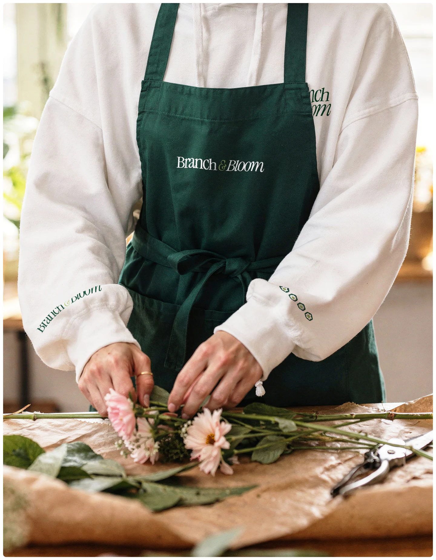 A florist in a branded apron arranging flowers