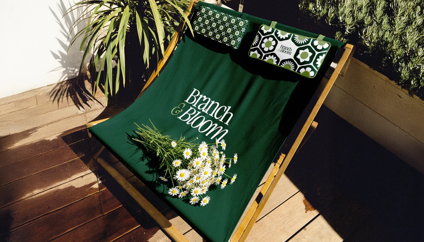 A deep-green deck chair with the wordmark and white flowers