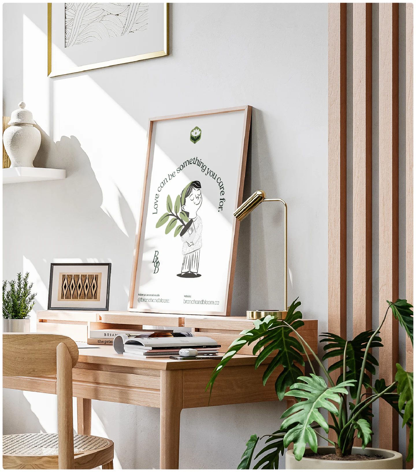 A framed print on a desk beside plants