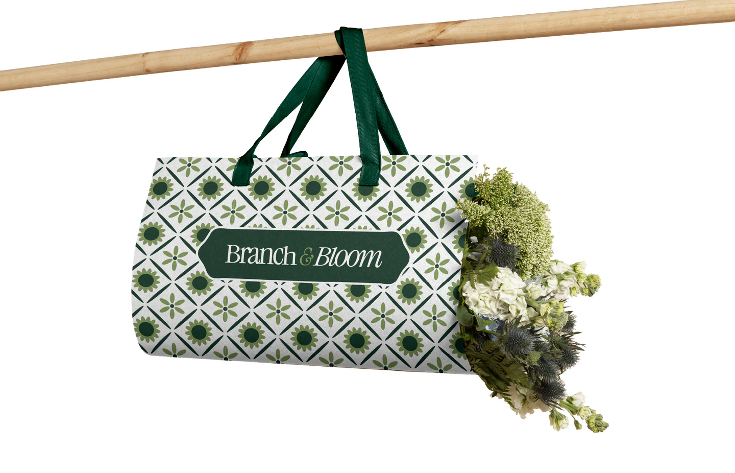 A patterned duffel bag hanging from a pole, filled with greenery