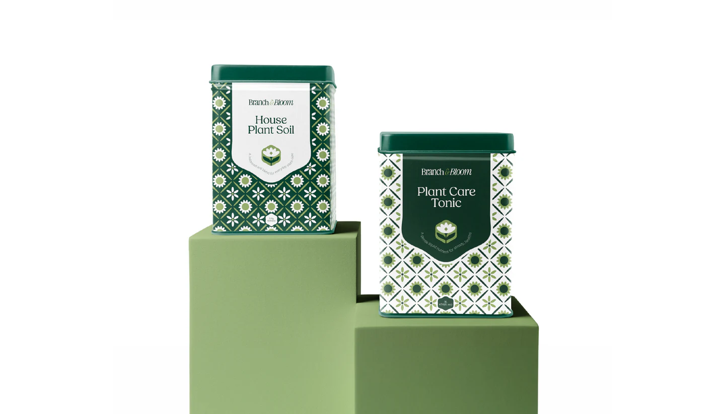 Two patterned tins on sage plinths