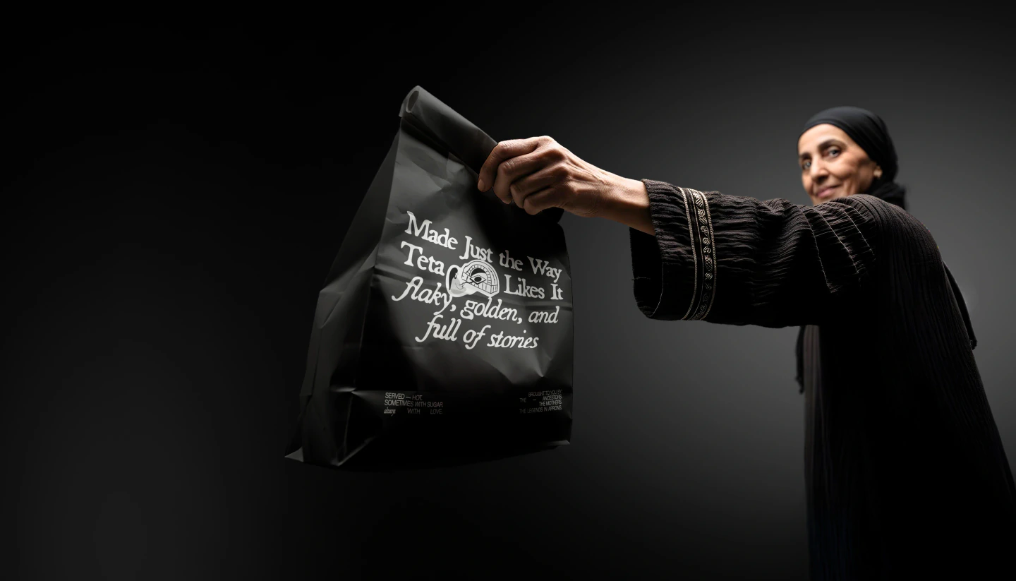 A woman in a black galabeya hands over a black SEDR takeaway bag