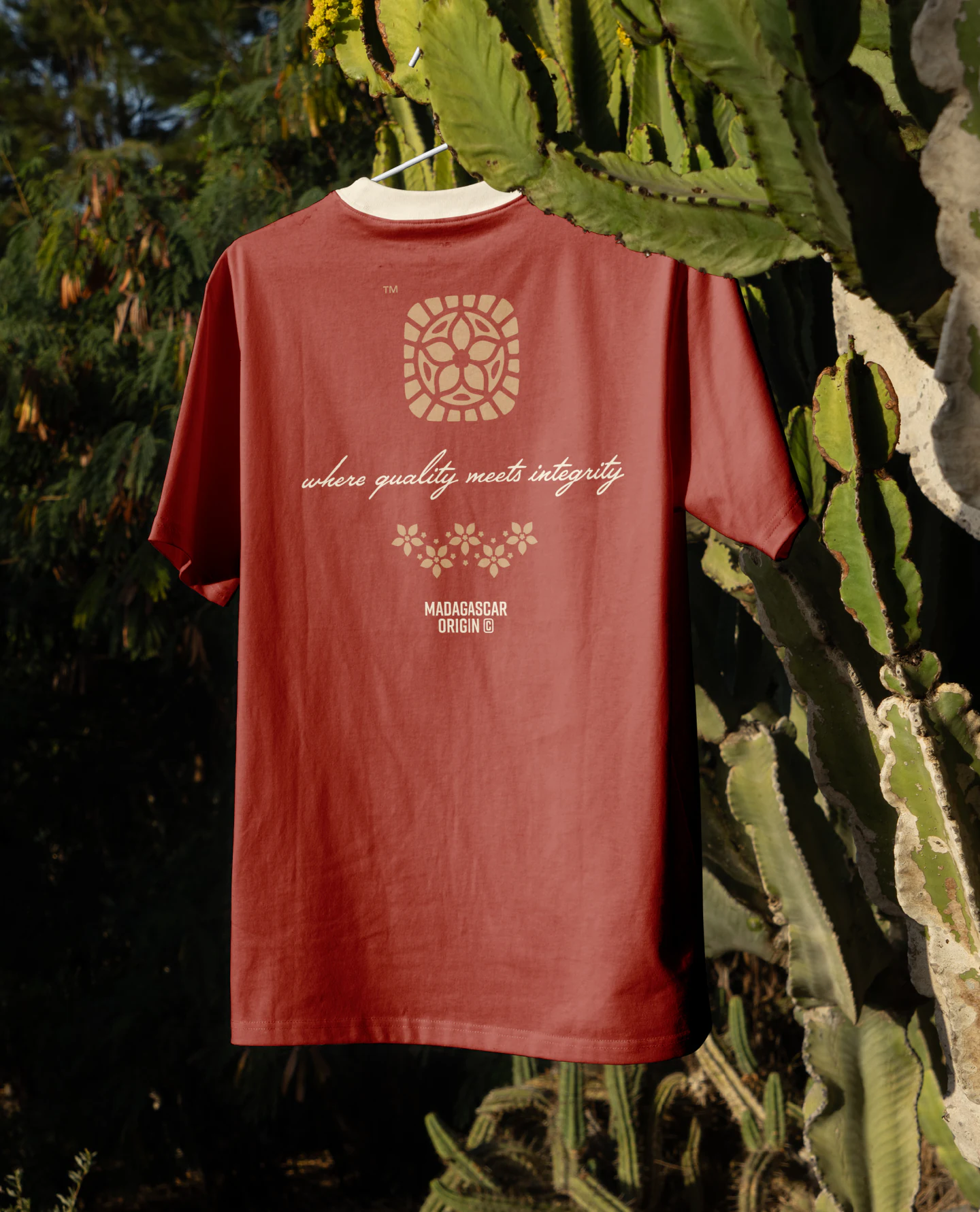 The red Vanilla Fair tee hanging among plants