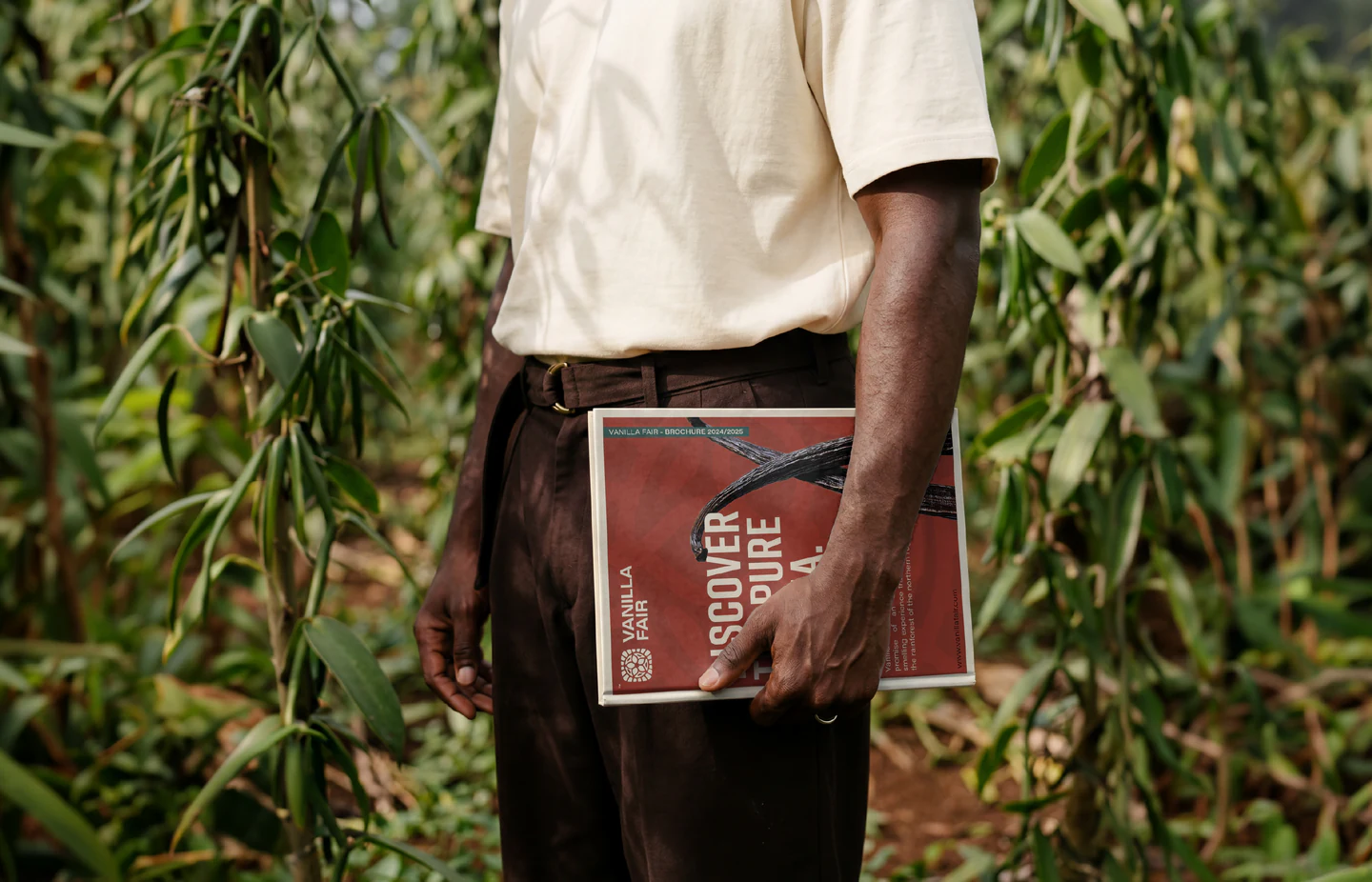 A farmer holding the catalog among the vines