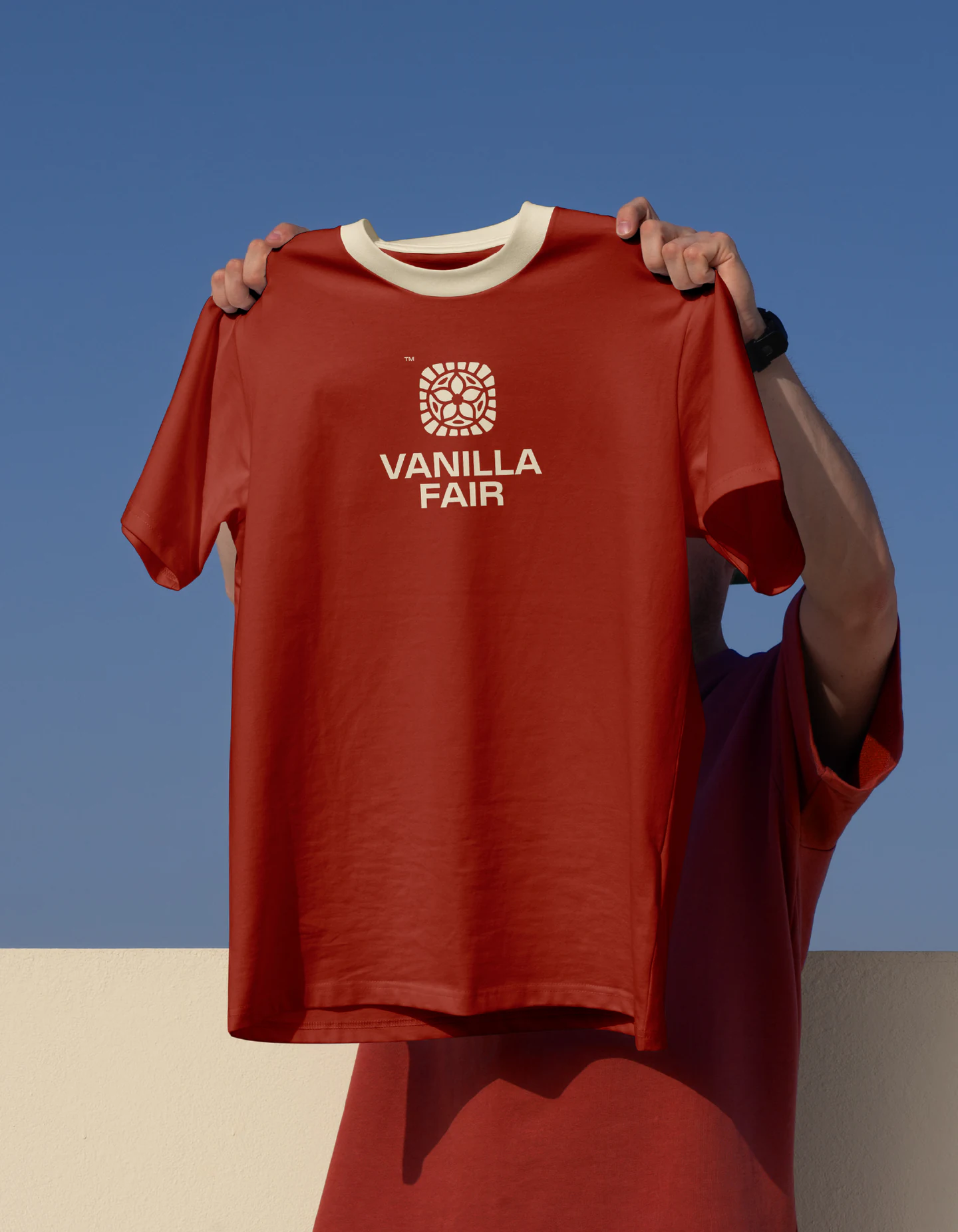 The red tee held up against the sky